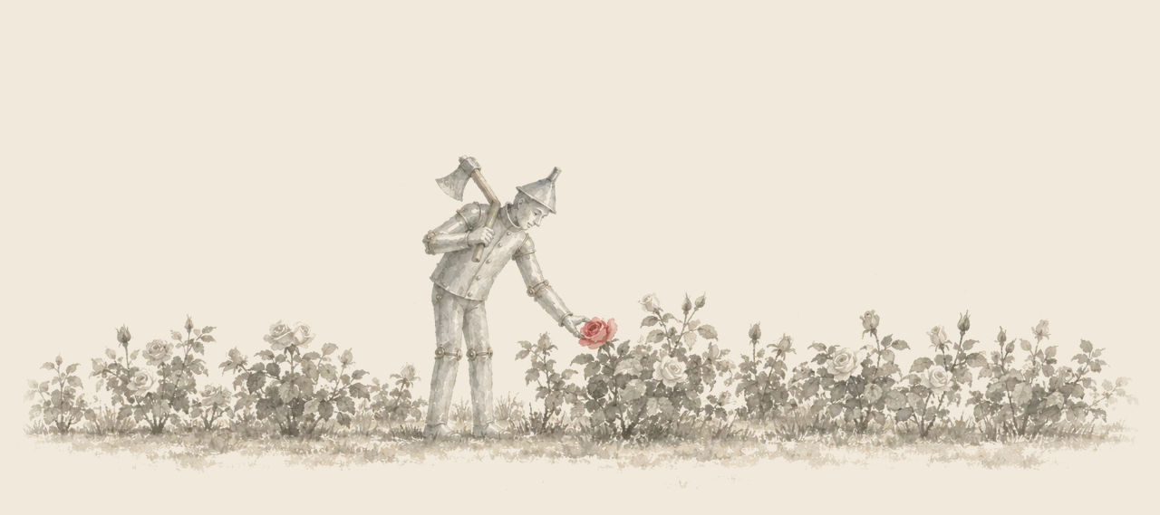 The Tin Woodman, axe on his shoulder, bends to pick a single red rose from a row of rose bushes in a garden.
