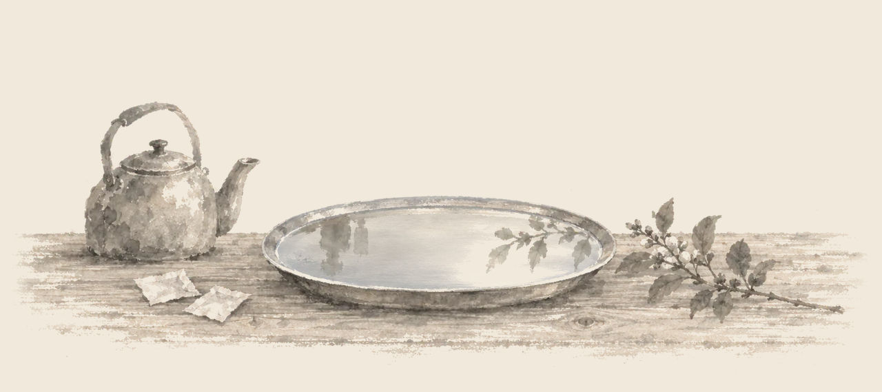 On a wooden table, a broad platter of broth lies smooth as a mirror beside a kettle, two empty paper packets and a small leafy branch.