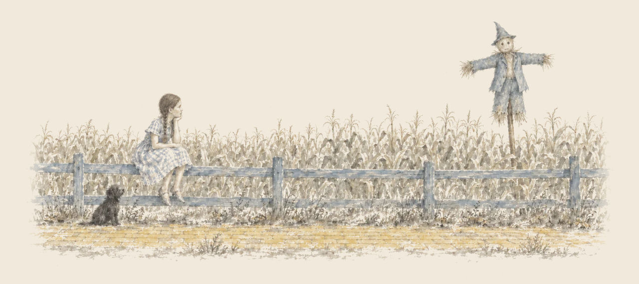Dorothy sits on a fence rail beside the yellow brick road, looking at the Scarecrow on his pole above the corn; Toto waits below.